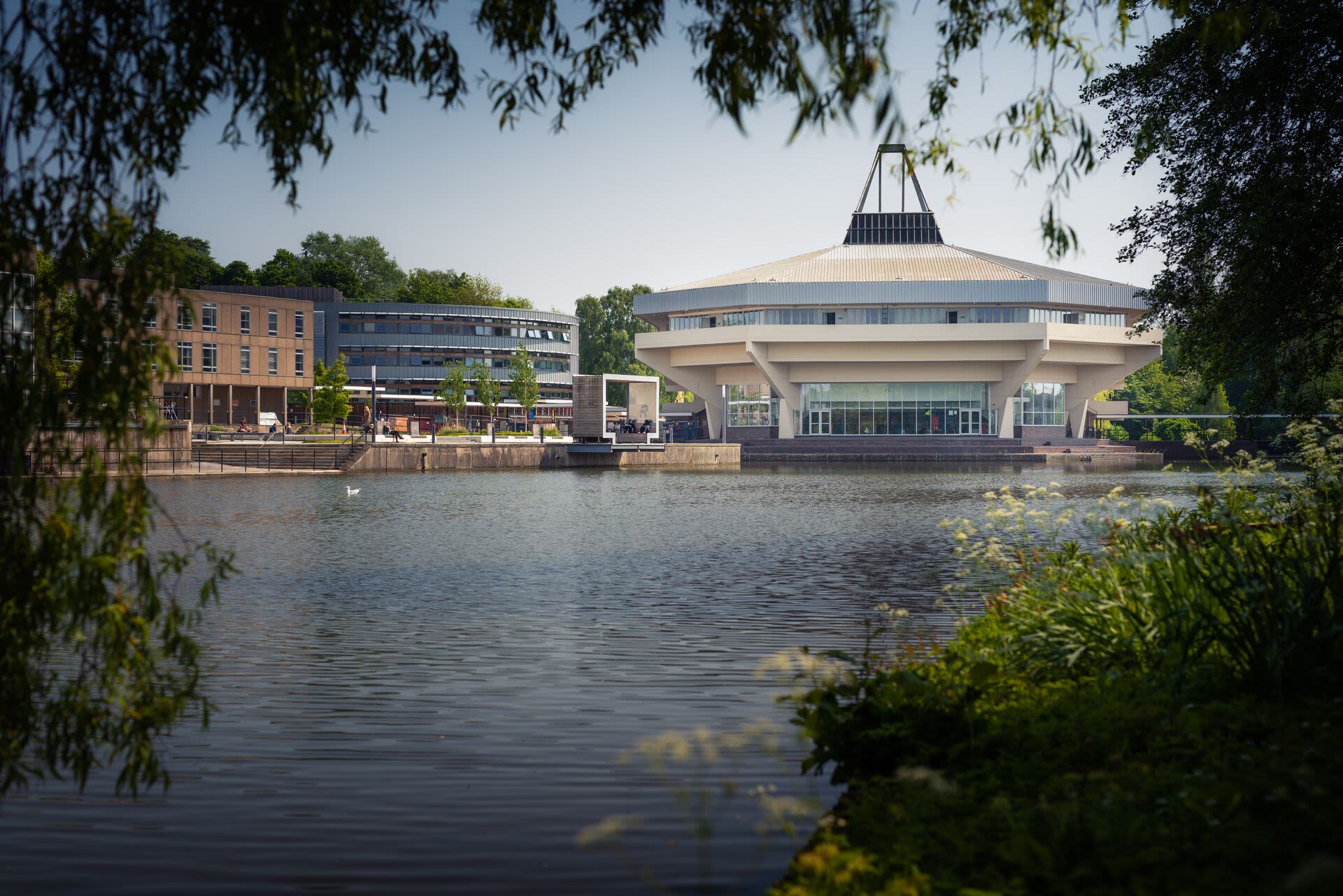 A view of central hall with the fountain running in front of it from the perspective of daffodils across the lake