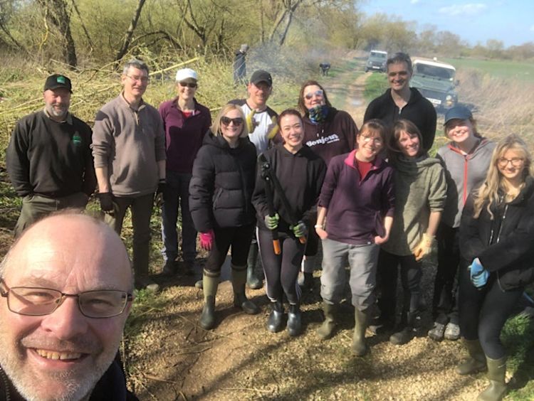 A large group of people wearing outdoor gear and gardening gloves. 