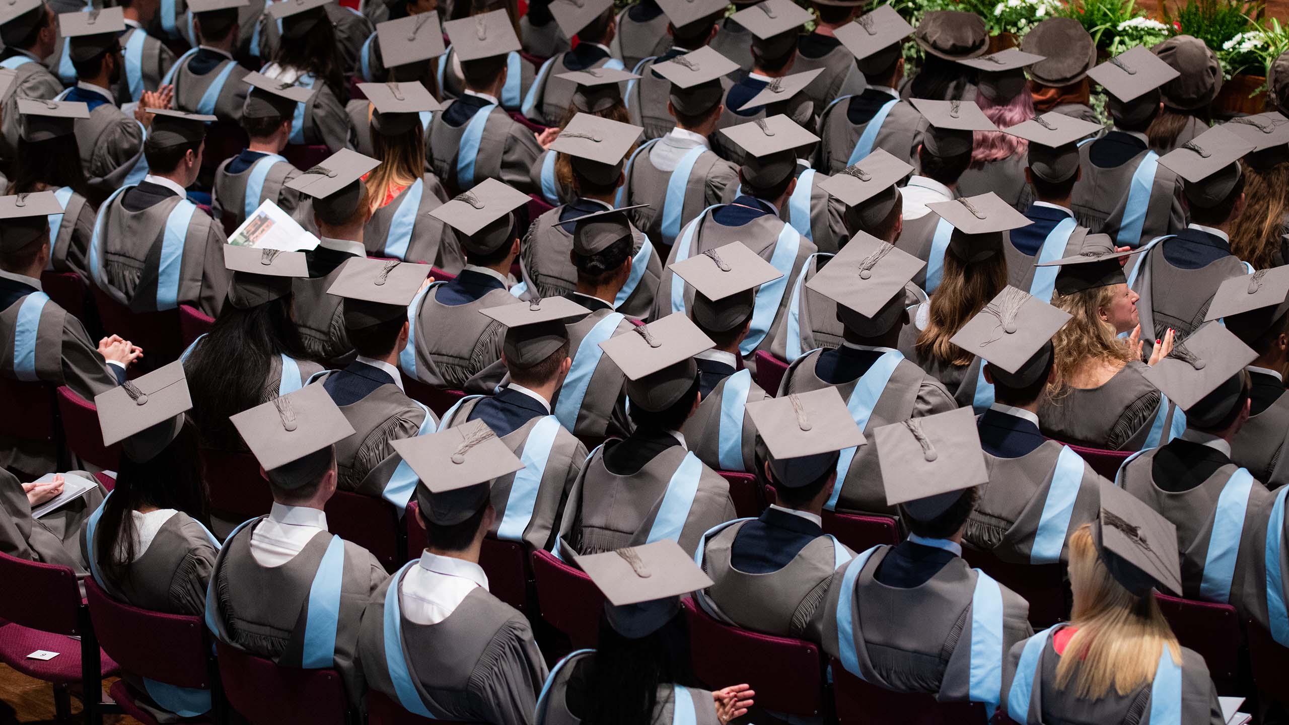 Students in gowns and caps attending graduation ceremony.