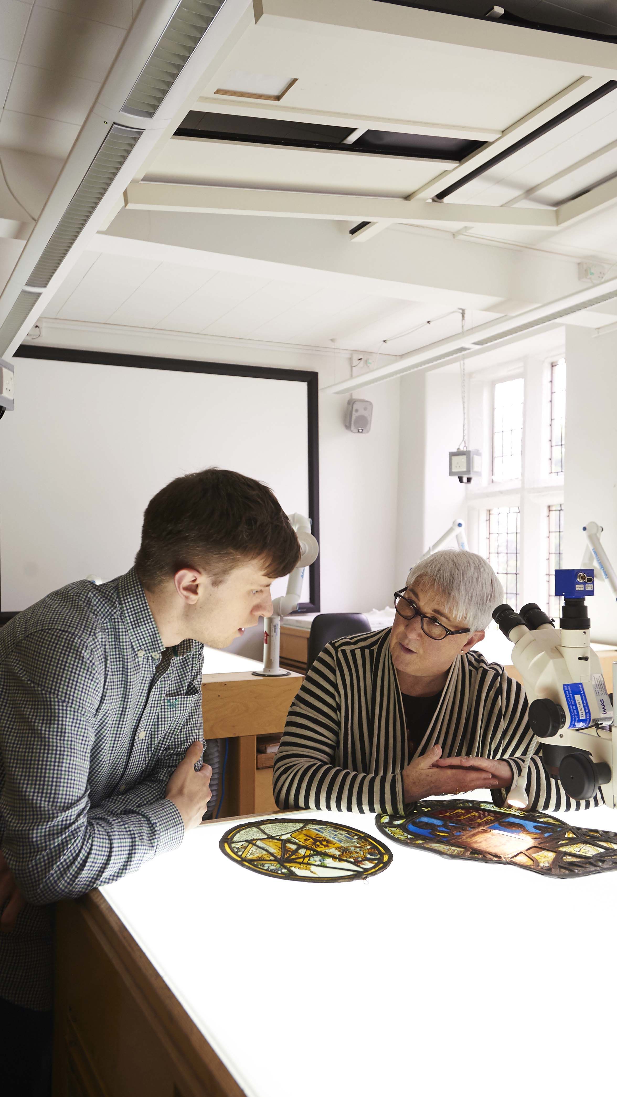 Student and member of academic staff studying stained glass in the Department of History of Art.