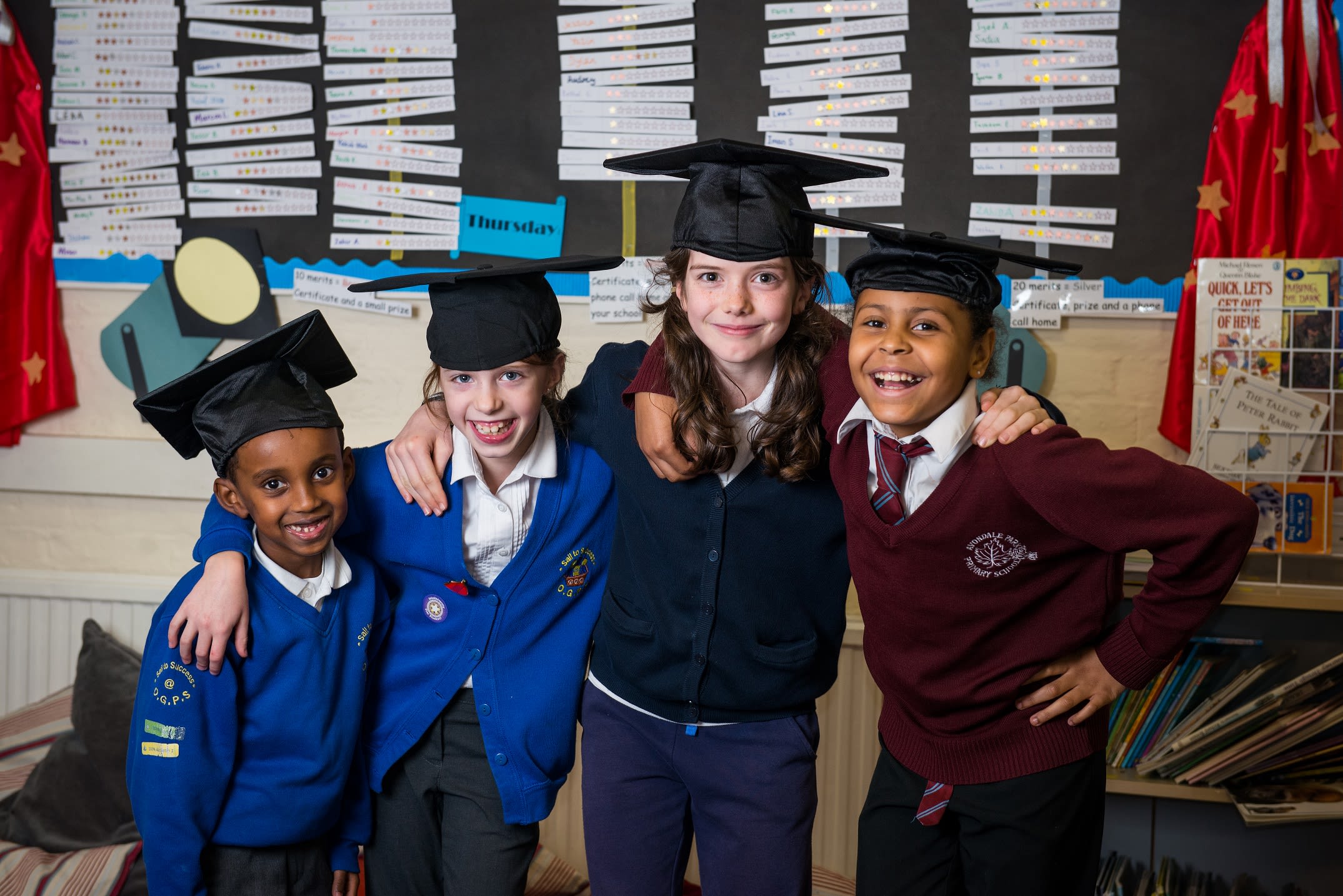 Image of four children wearing graduation caps 